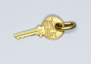 A novelty charm modelled as a key and inscribed 'Apri Il Tuo Cuore', the bail marked '750', length