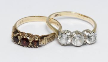 A hallmarked 9ct gold three stone garnet ring and another ring set with colourless stones and