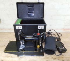A Singer Featherweight 221K electric travel sewing machine with case and accessories.