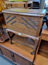 A vintage oak cantilever sewing box containing various needles, threads, buttons and accessories.