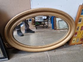 An early 20th century oval gilt framed mirror, 76cm x 51cm.