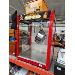 A commercial popcorn machine with a number of popcorn boxes/bags.