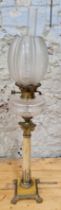 A large oil lamp with clear glass resevoir and corinthian column, Height 86cm.