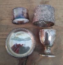 A mixed lot of hallmarked silver comprising two serviette rings, an egg cup and a tray, weight 153g.