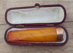 A cased hallmarked 9ct gold mounted butterscotch amber cheroot holder.