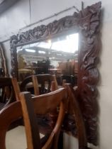 An Edwardian Arts & Crafts carved oak framed mirror.
