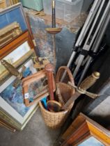 A wicker basket containing various sporting equipment to include epees, squash and badminton