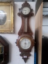 A Victorian carved oak barometer with clock.