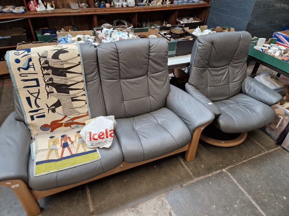 An Ekornes Stressless grey leather two seater sofa and matching swivel armchair.