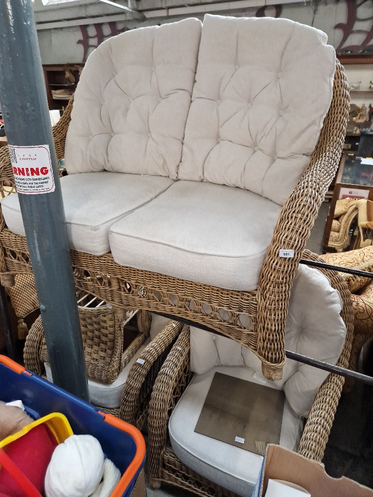 A cane conservatory suite comprising two seater sofa, two armchairs and a coffee table.