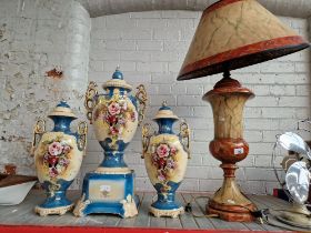 A garniture of urns and a large table lamp.