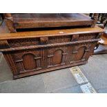 A aged oak coffer with carved panels.