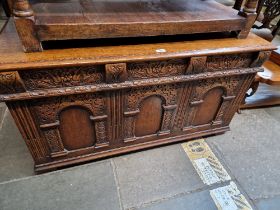 A aged oak coffer with carved panels.