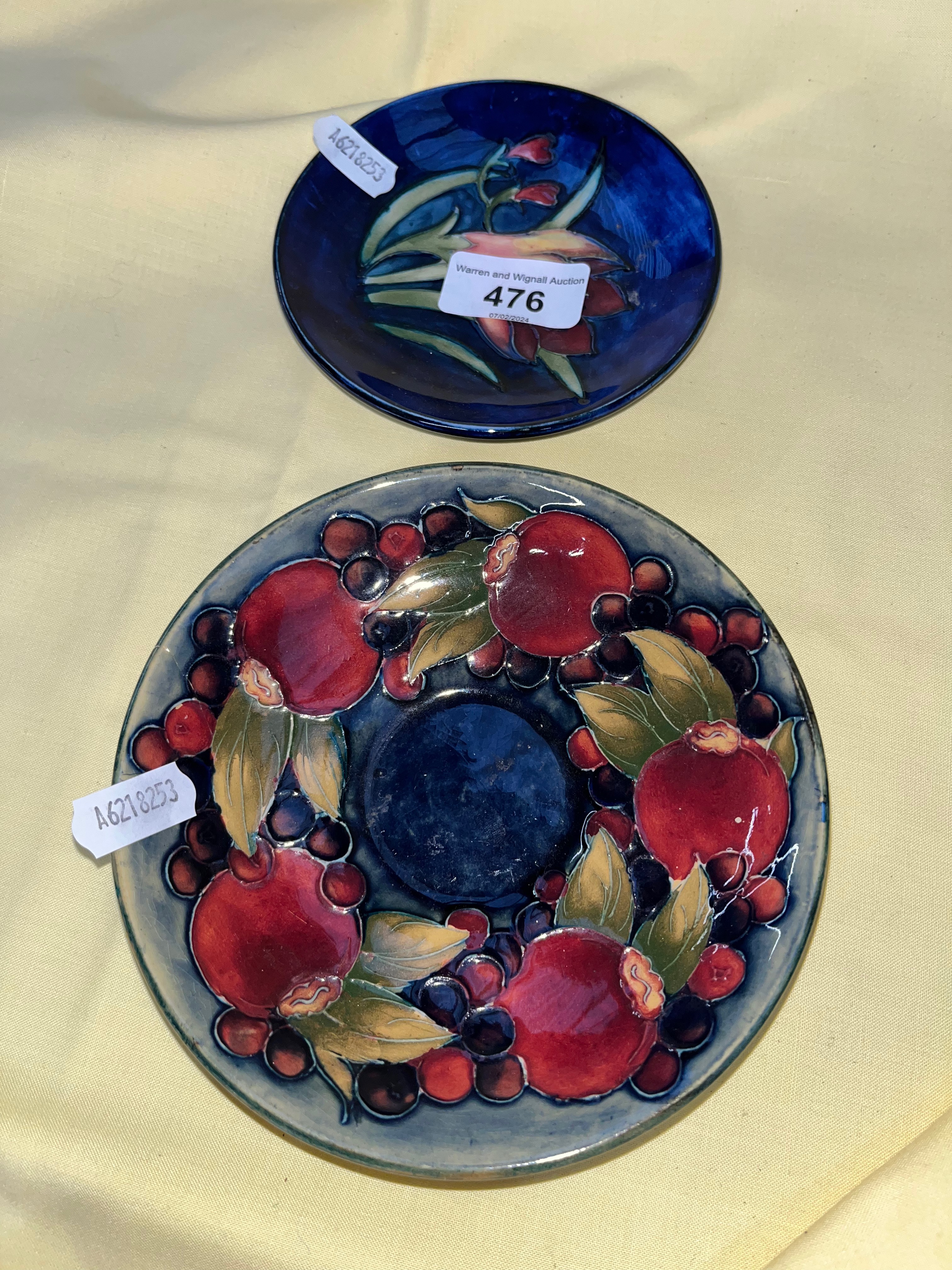 A Moorcroft pin dish, diam appx 12cm, and a Moorcroft saucer diam 14cm.