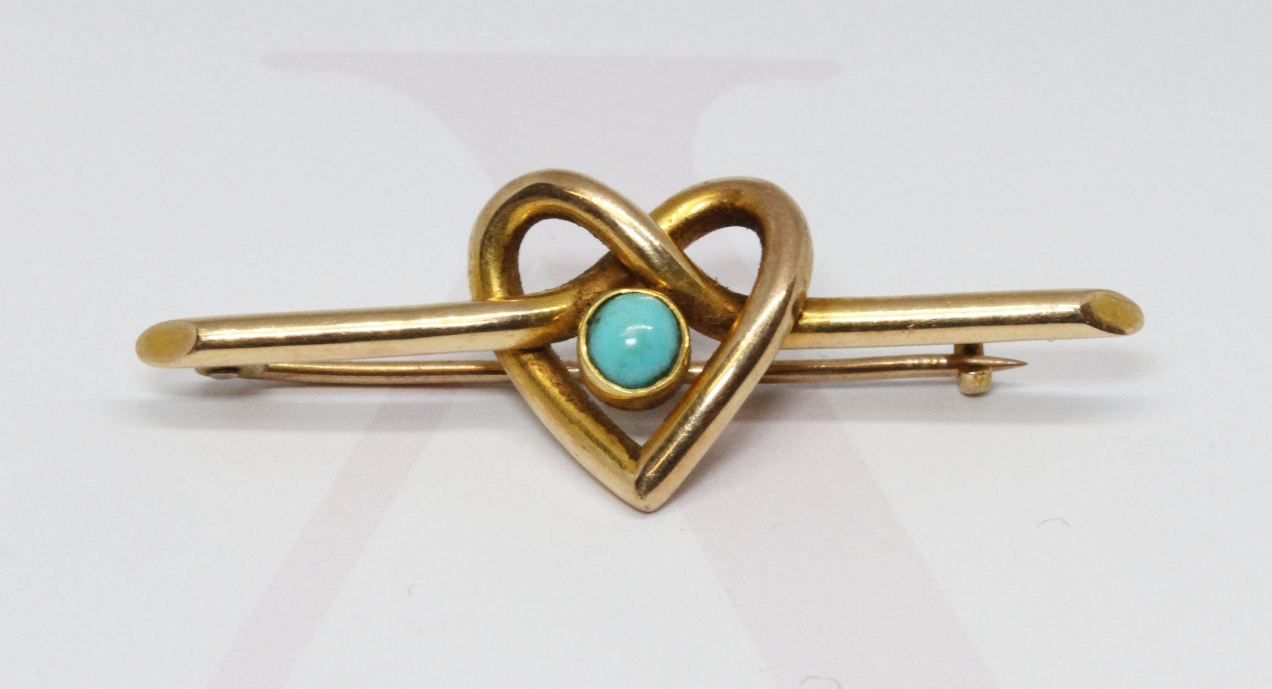 An Edwardian bar brooch formed from an entwined heart design with central turquoise cabochon, marked