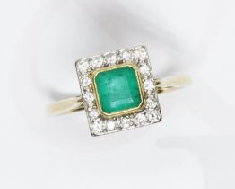An emerald and diamond cluster ring, the yellow gold bezel set emerald measuring approximately 5.