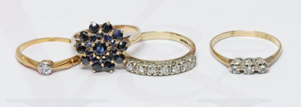 A group of four rings comprising three 9ct gold and one three stone diamond ring indistinctly