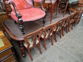 A large Victorian mahogany wind out dining table and ten chairs, the table having reeded legs and