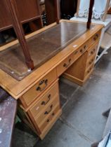 A golden oak twin pedestal desk with tooled leather top.