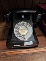 A vintage black bakelite telephone.