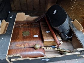 A hanging pendulum clock, two boxes and a pair of binoculars.