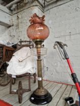 A brass and glass paraffin lamp with cranberry glass shade.