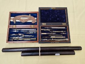 Two cased drawing instrument sets together with two rolling rulers (one ebony, one rosewood).