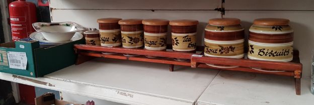 A collection of 7 storage jars in 3 sizes by Tom Raymond Pottery, set on a wooden stand, together