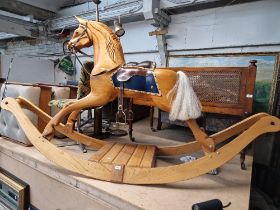 A modern large wooden rocking horse, no maker's label, leather saddle and tack.