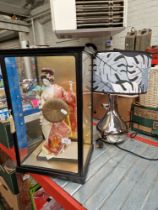 A cased Geisha, an earthenware bread crock and a table lamp.