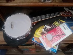 A Vangoa banjo ukulele with bag, accessories and books.