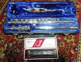 A silver plated Buescher flute and a harmonica.