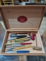 A cigar box and containing various collectables including Parker pens, dip pens, cherry amber