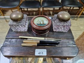 An oak desk stand with glass inkwells together with Parker pens, propelling pencils and a wooden pot