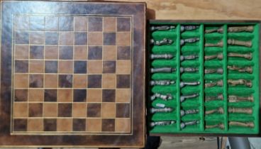 A tooled leather chess board, with cast metal chess pieces in fitted drawer.
