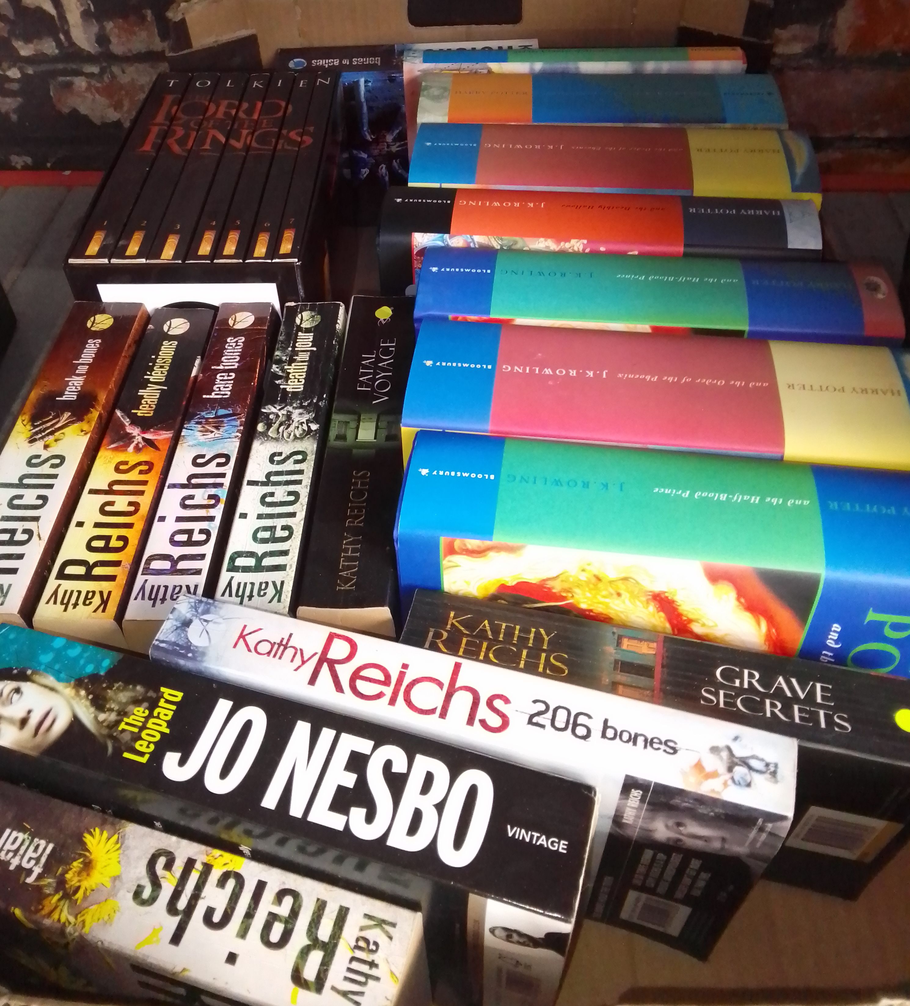 A box of books including 7 Harry Potter hardbacks, Kathy Reichs paperbacks, and Lord of The Rings