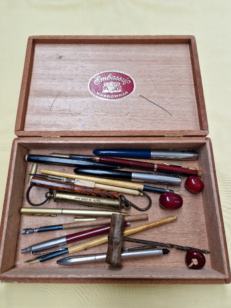 A cigar box and containing various collectables including Parker pens, dip pens, beads, etc.
