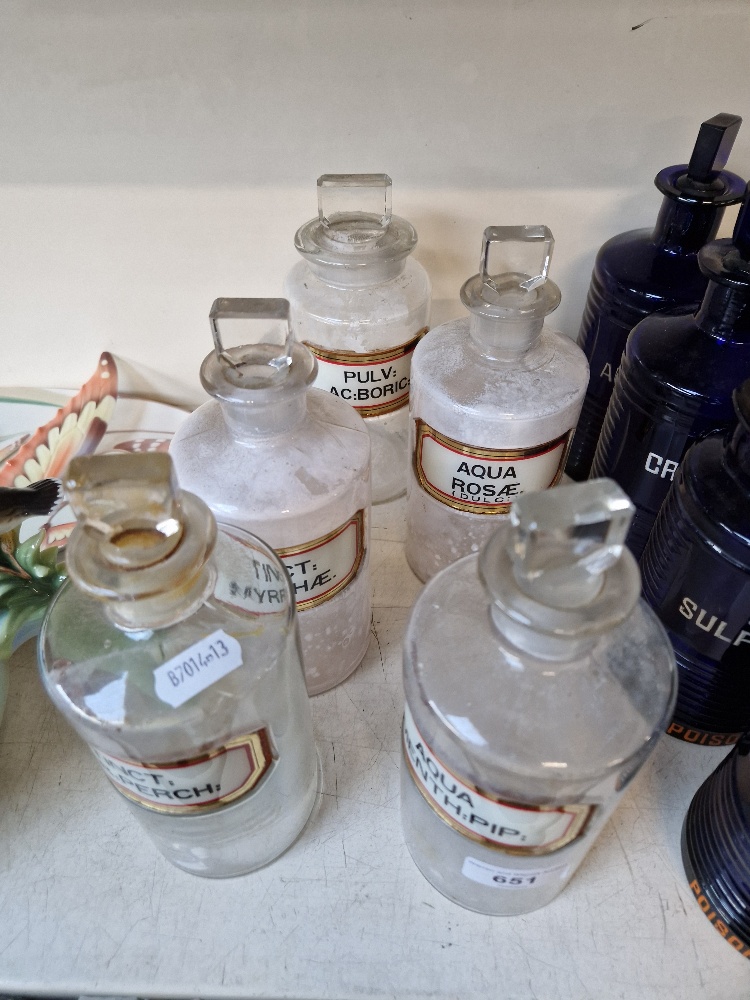 A group of five clear glass apothecary bottles