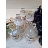 A group of five clear glass apothecary bottles