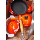 A ox containing 3 Le Creuset sauce pans and a Le Creuset style frying pan and casserole dish