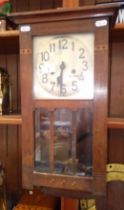 An early 20th century wall clock with pendulum and key.