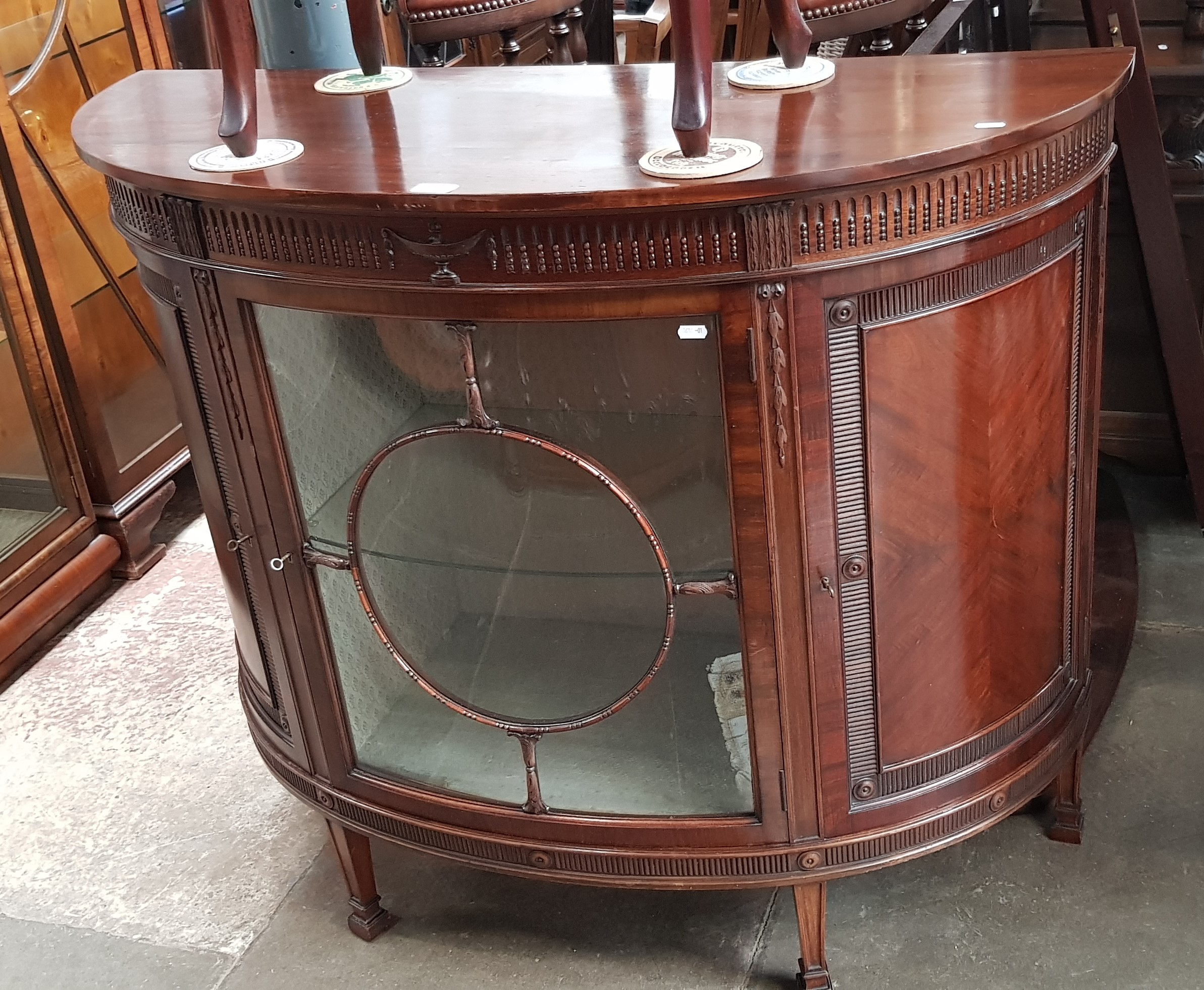 An early 20th century mahogany demi-lune display cabinet.