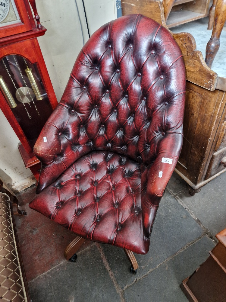 An oxblood red leather Chesterfield swivel chair.