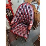 An oxblood red leather Chesterfield swivel chair.