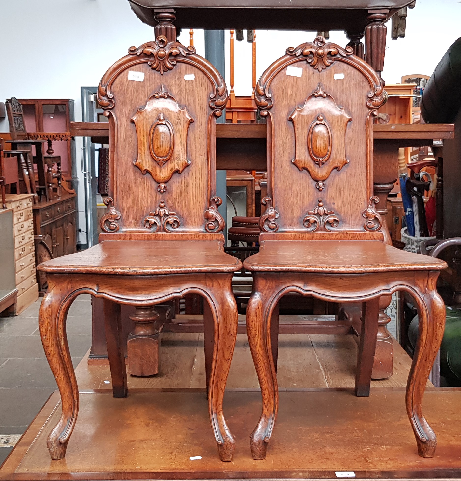 A pair of 19th century oak hall chairs with cabriole legs.
