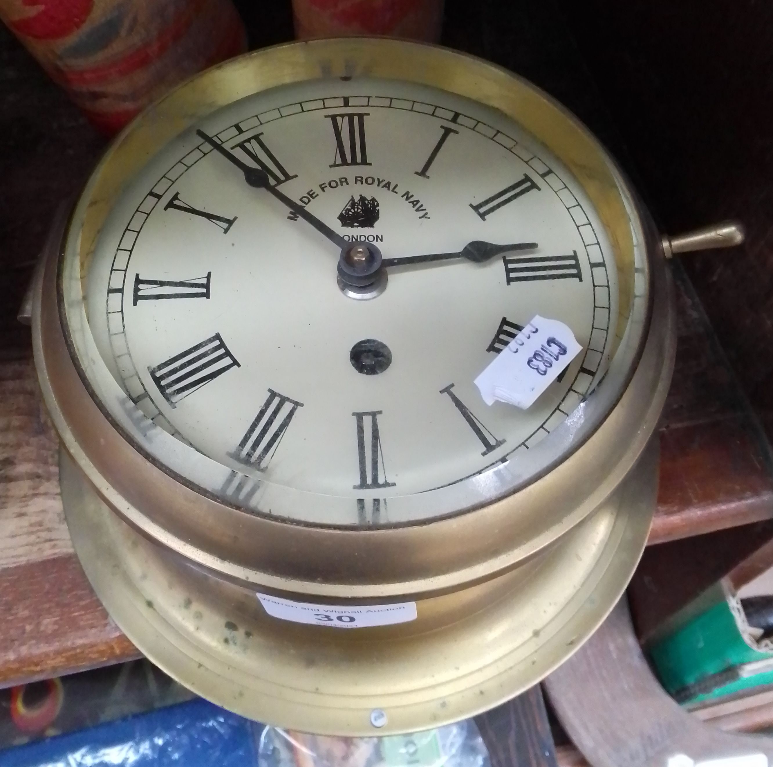 A repro clock mechanism with Made for Royal Navy on clock face in a brass porthole style case