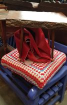 A red cow hide rug, a vintage stool and a vintage solid wood table.