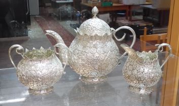 An Egyptian three piece silver tea set, profusely decorated with flowers, cobra snake handles,