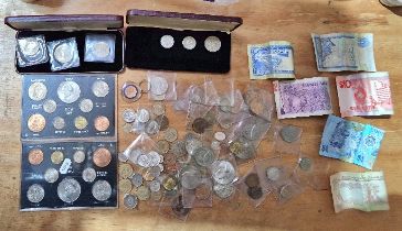 A collection of UK and world coins including cased coin sets and banknotes.