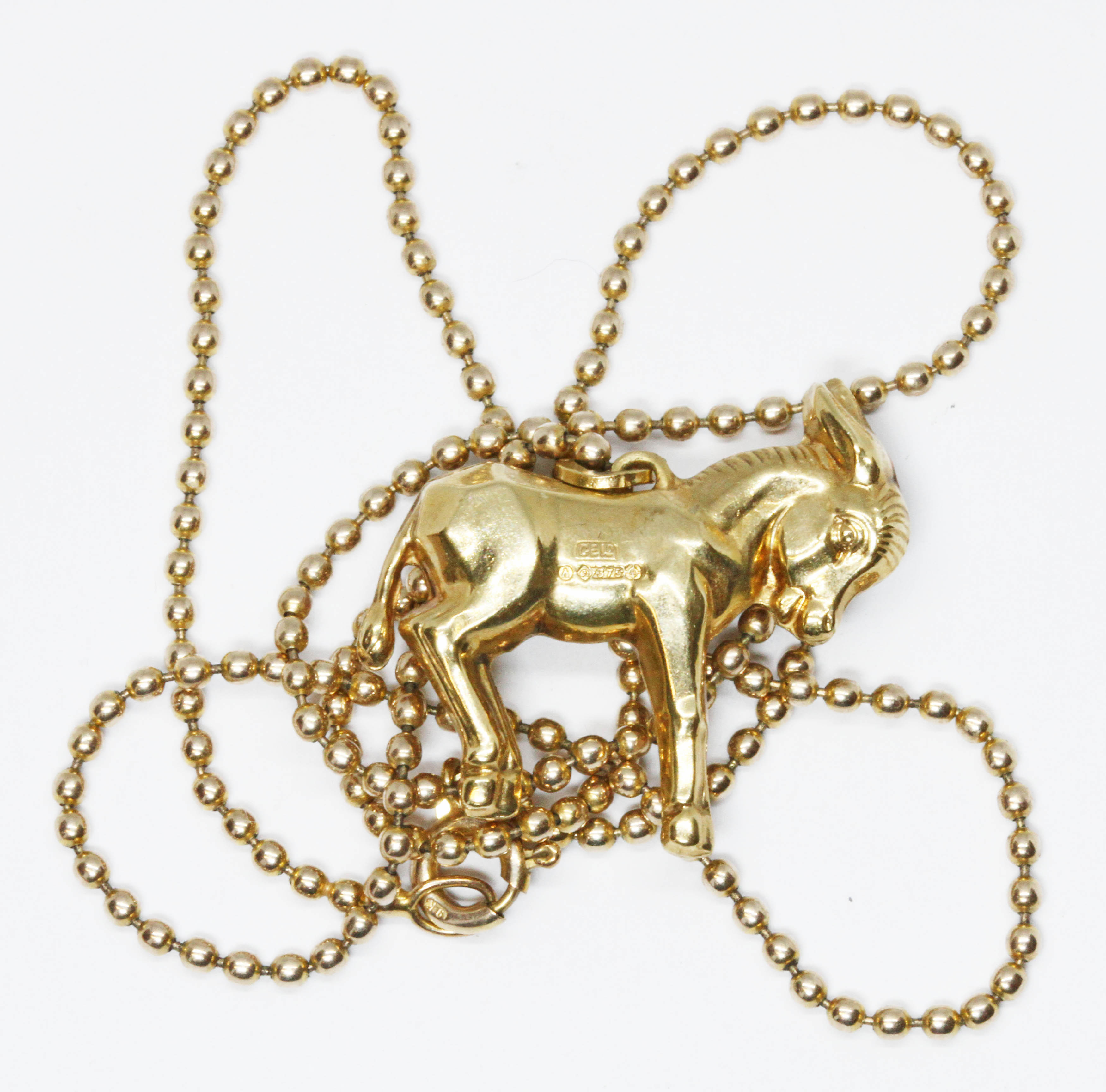 A 9ct gold novelty pendant modelled as a donkey, on 9ct 46cm bead link chain, both with import